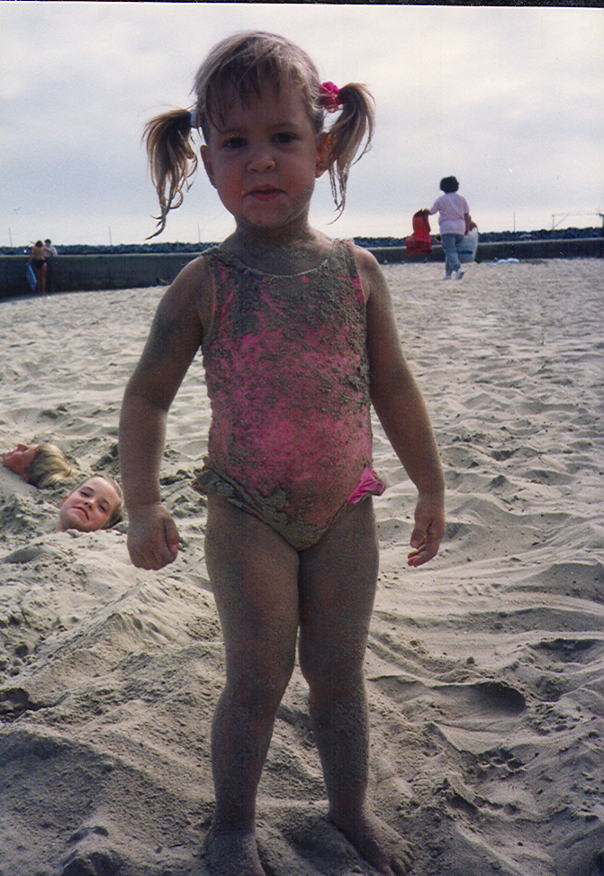Alyssa as a toddler, standing on the beach