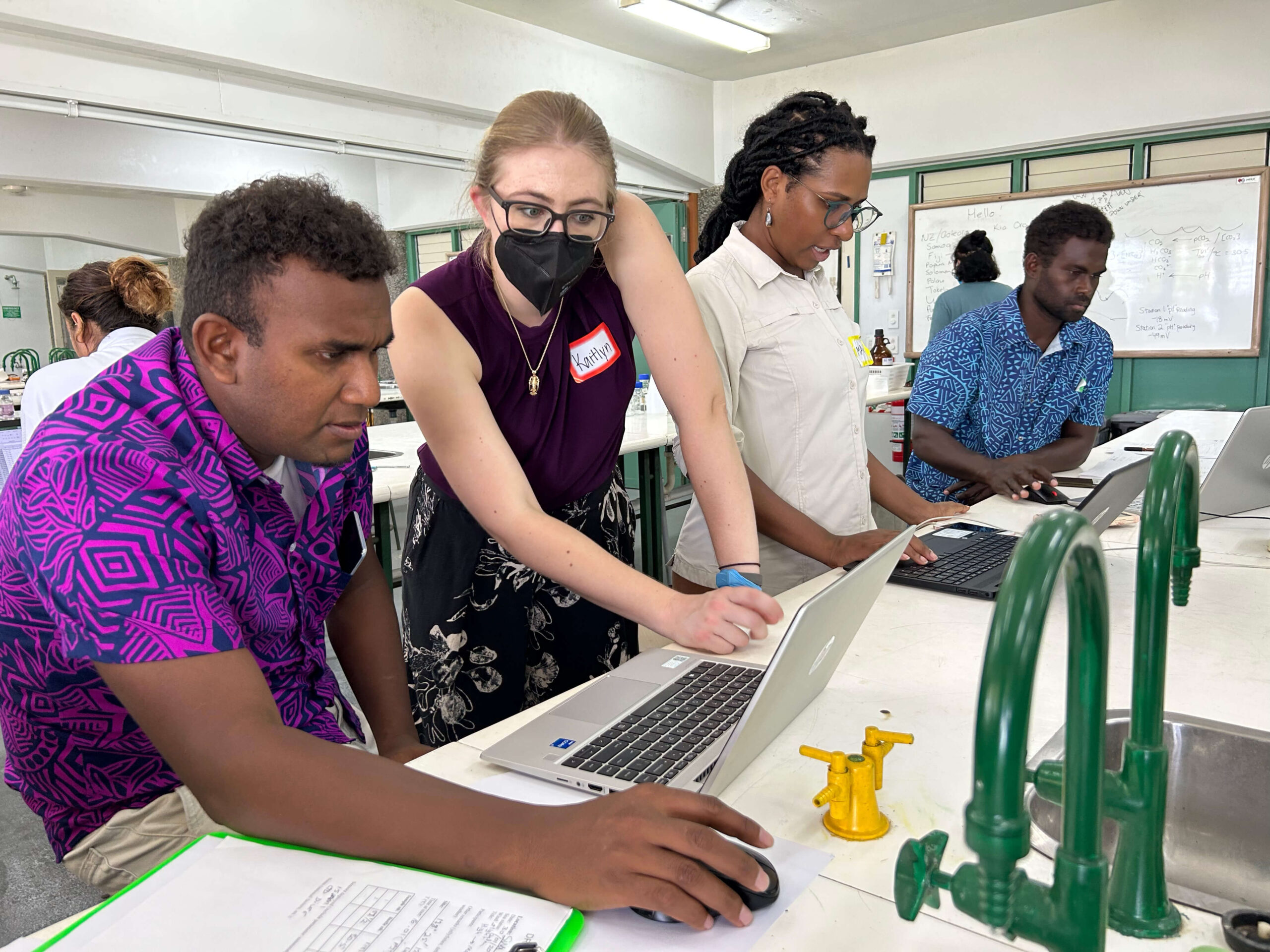 Kaitlyn zeigt auf einen Computer bei einem Training in Fidschi
