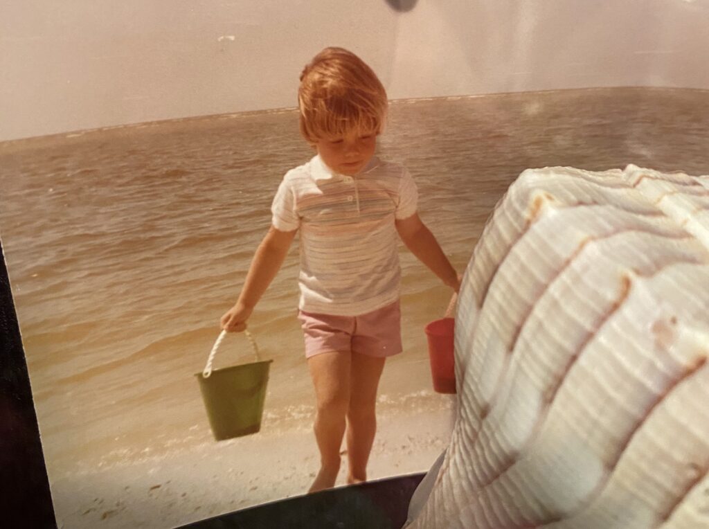 Kate as a toddler on the beach with a green bucket