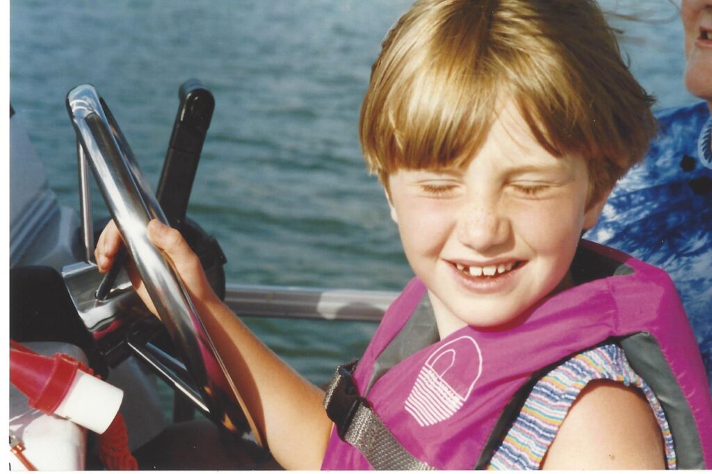 Katie helping driving a boat as a child at Ford Lake