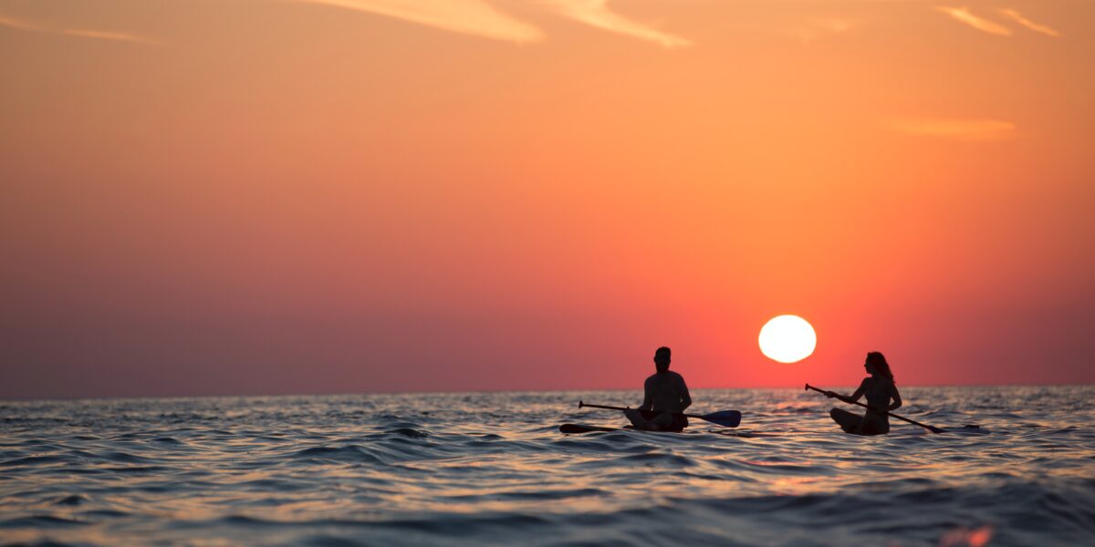 sunset on the ocean with paddlers