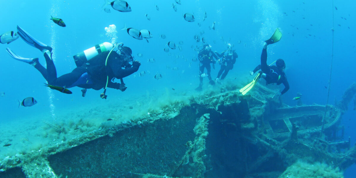 Scuba Divers Exploring underwater ship wreck