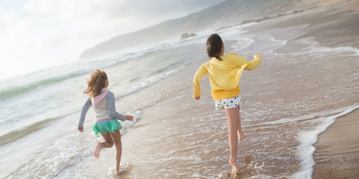 Two children running towards the water at the beach