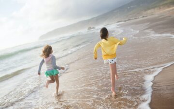 Two children running towards the water at the beach