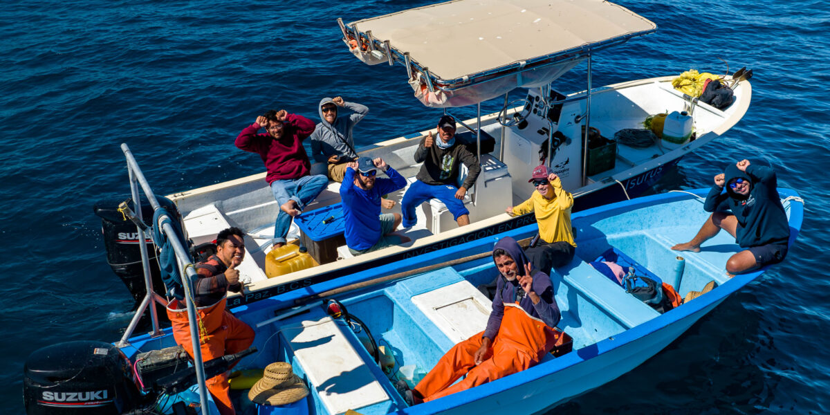 People on board two boats that are side by side in the water