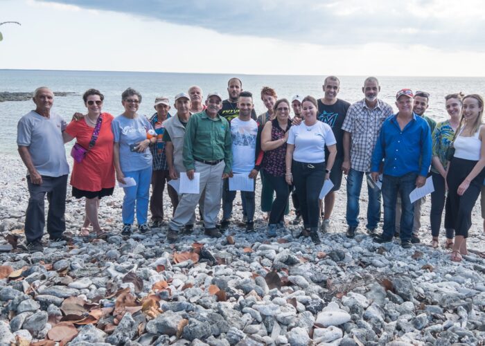 A group of people stand on a rocky beach.
