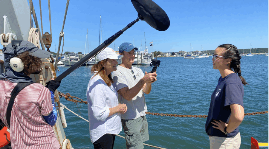 A film crew interviews a woman by the water.
