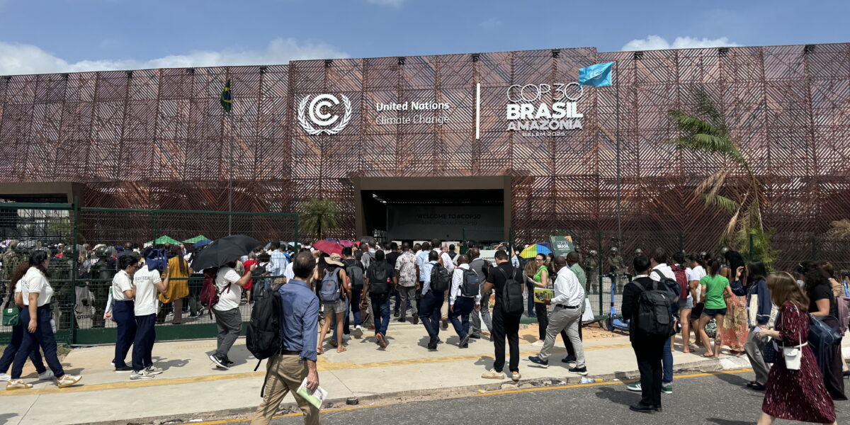 People walking into a building with a signthat says COP30 Brasil Amazonia.